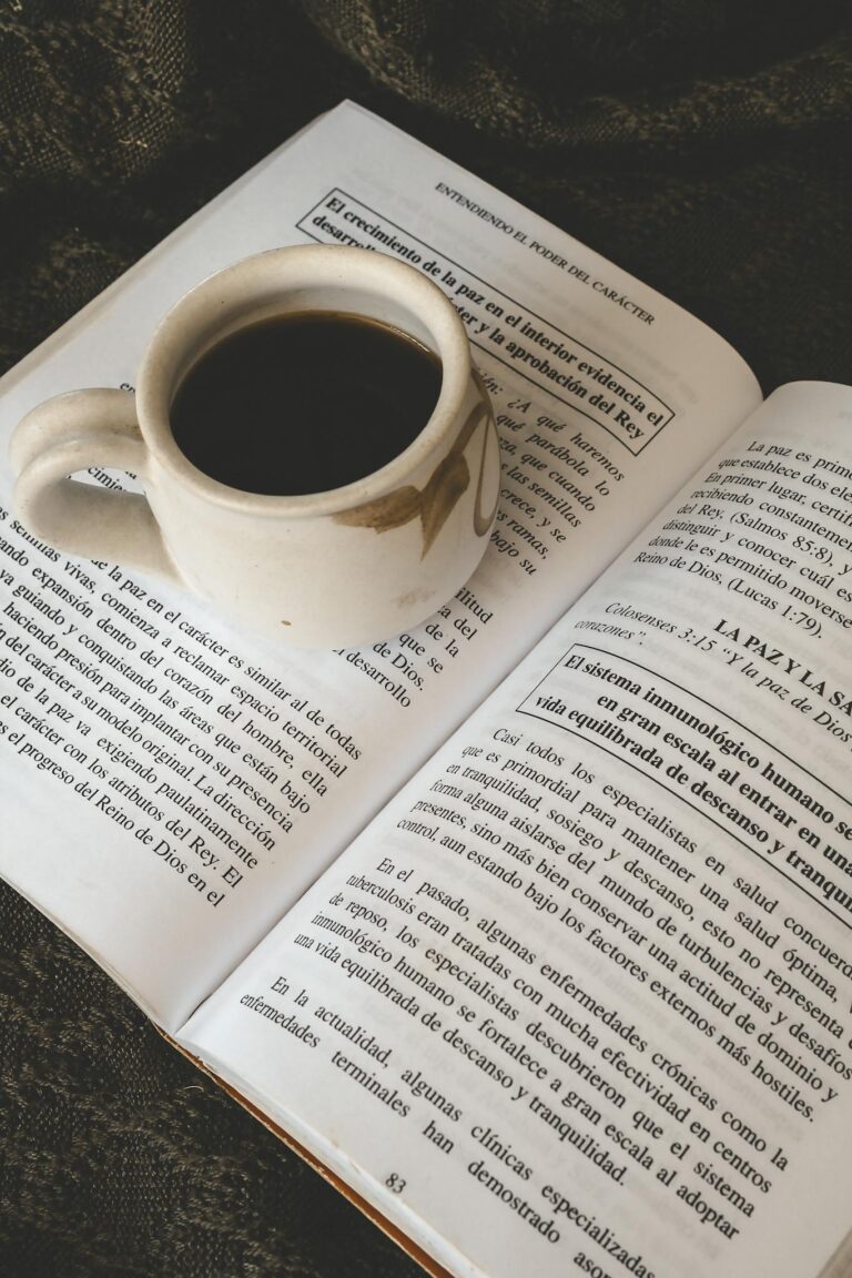 A cup of coffee resting on an open book, perfect for a cozy reading session.