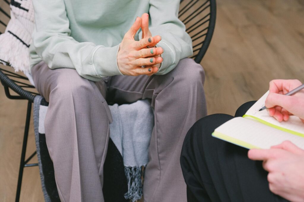 crop psychologist writing in notebook against patient